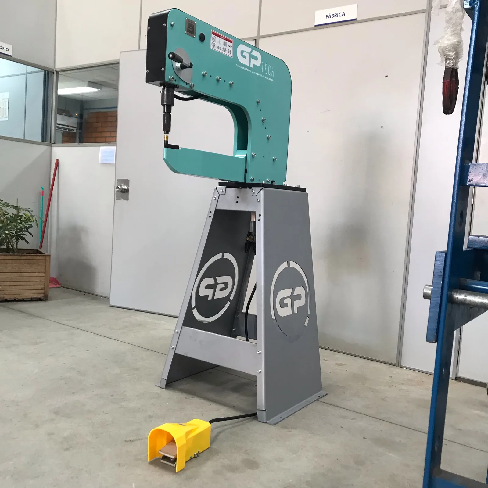 Ponteadeira GPTECH verde-água sobre pedestal, no chão da fábrica.