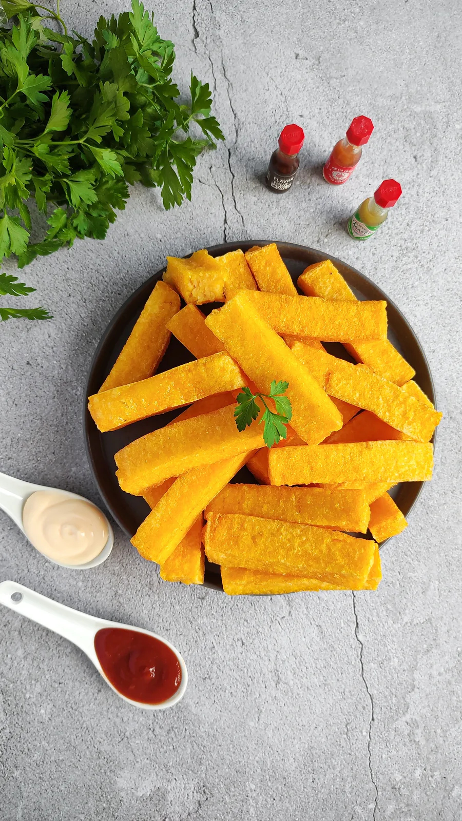 Polenta palito da Momil servida num prato, com potinhos de molho.